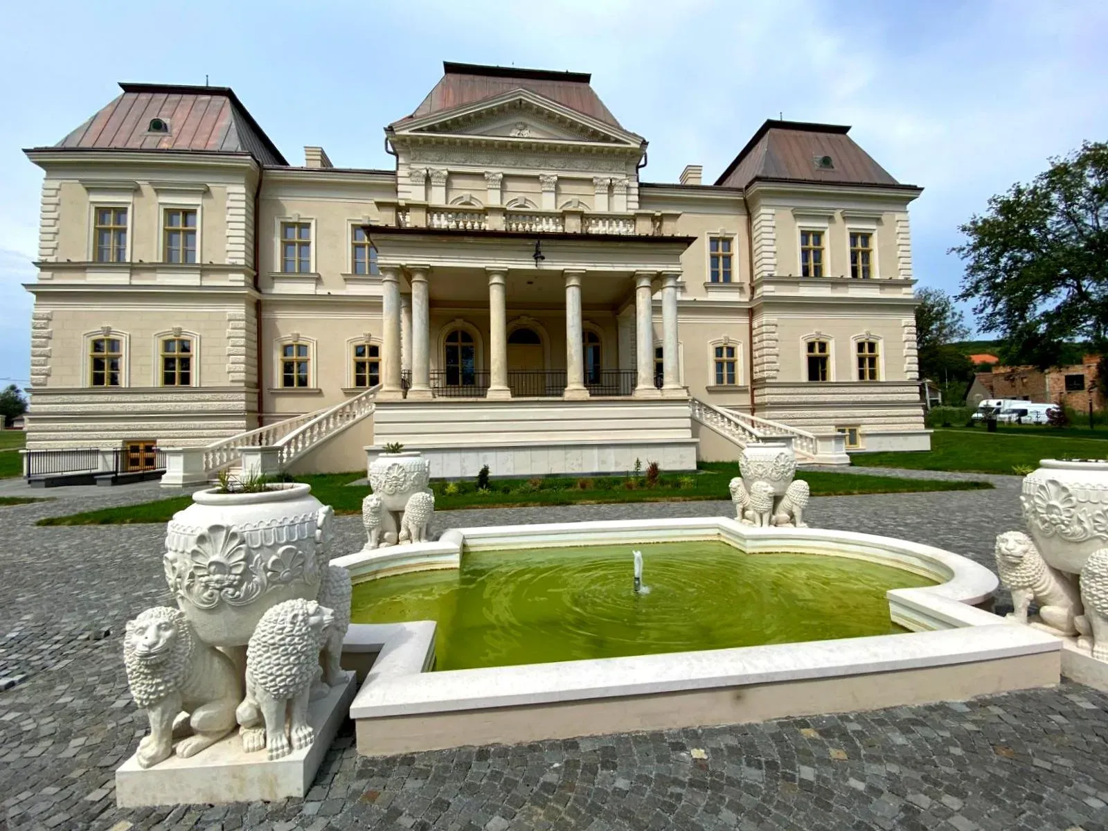 Fațada restaurată a Castelului Bánffy din Răscruci, cu fântâna din fața intrării
