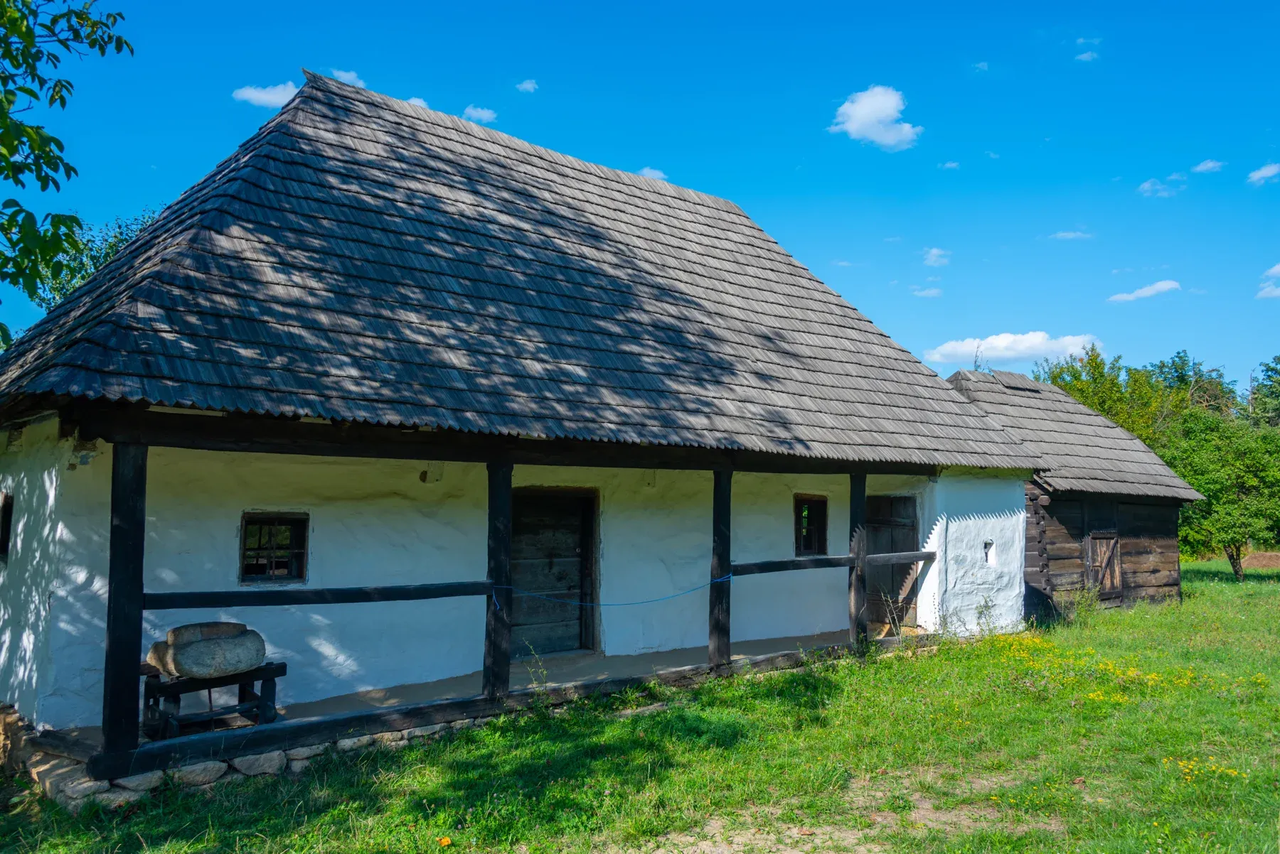 A house with whitewashed walls and a porch, under a shingle roof